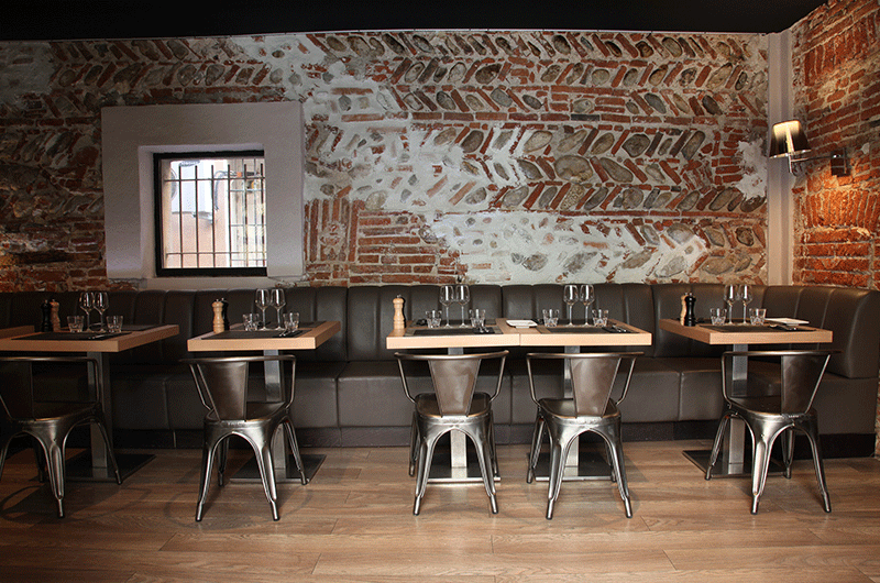 Restaurante de estilo industrial con mesas de madera y sillas metálicas decorada por PortobelloStreet